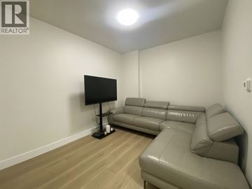 Burnaby apartment for rent - A living room with a grey couch and a black television.
