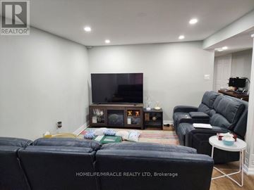Mississauga (Streetsville) apartment for rent - A living room with a black leather couch and a flat screen TV mounted on the wall.