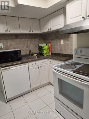 Toronto (Birchcliffe-Cliffside) apartment for rent - A kitchen with white cabinets and a black microwave.