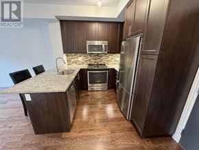 Mississauga (Erin Mills) condo for rent - A kitchen with dark wood cabinets and stainless steel appliances.
