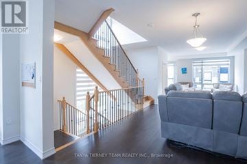 Whitby (Brooklin) townhouse for rent - A living room with a grey couch and a staircase with wooden railings.