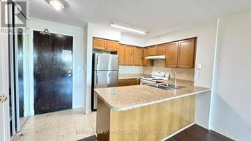 Toronto (Willowdale East) condo for rent - A kitchen with a granite countertop and wooden cabinets.