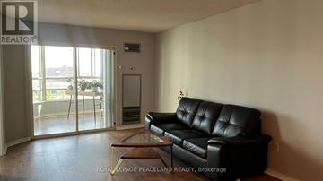 Markham (Aileen-Willowbrook) condo for rent - A black leather sofa sits in a living room with a glass door leading to a balcony.