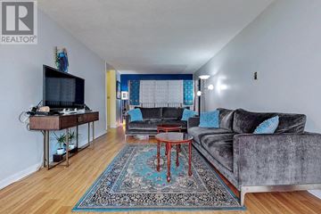 Toronto (Eglinton East) condo for rent - A living room with a grey couch and a television on a wooden stand.