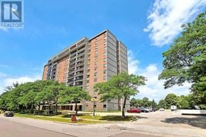 Toronto (Eglinton East) condo for rent - A tall apartment building with a parking lot in front.
