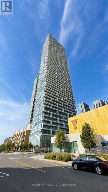 Vaughan (Vaughan Corporate Centre) condo for rent - A tall building with a glass facade stands next to a smaller building with a yellow facade.
