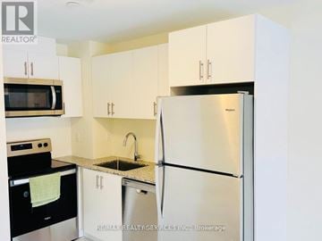 Toronto (Malvern) townhouse for rent - A kitchen with white cabinets and a stainless steel refrigerator.
