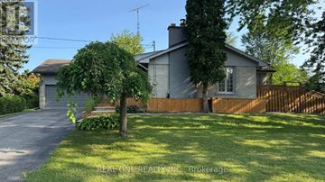 Richmond Hill (South Richvale) apartment for rent - A house with a grey roof and a brown fence is surrounded by green grass and trees.