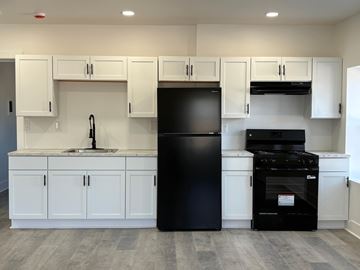 Ashtabula apartment for rent - A black refrigerator and oven in a kitchen with white cabinets.