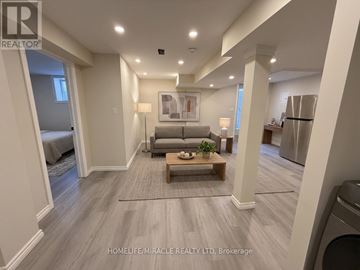 Oshawa (Taunton) apartment for rent - A spacious living room with a grey sofa and a wooden coffee table.