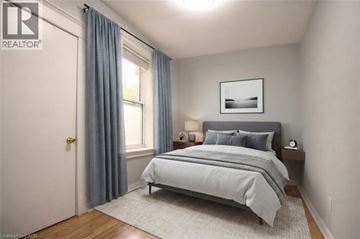 Hamilton apartment for rent - A bedroom with a bed, nightstand, and window.