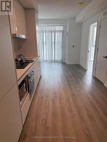 Oshawa (Windfields) condo for rent - A kitchen with wooden floors and white cabinets.