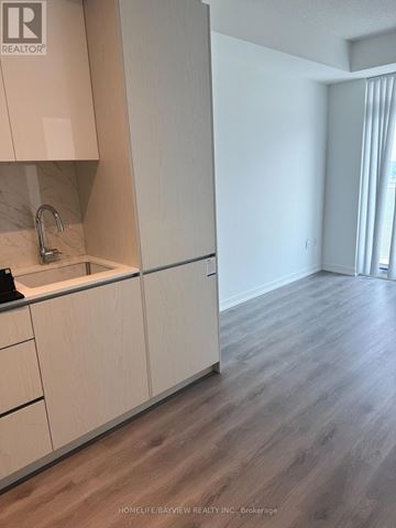 Oshawa (Windfields) condo for rent - A kitchen with white cabinets and a wooden floor.