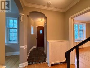 Toronto (Bedford Park-Nortown) multi-family for rent - A hallway with a wooden floor, a black railing, and a white radiator.