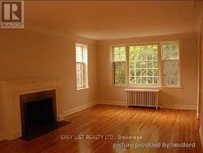 Toronto (Bedford Park-Nortown) duplex for rent - A room with a fireplace and a window with a view of trees.