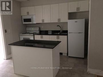 Toronto (Danforth Village-East York) apartment for rent - A kitchen with white cabinets and black countertops.