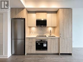 Toronto (Regent Park) condo for rent - A modern kitchen with wooden cabinets and stainless steel appliances.