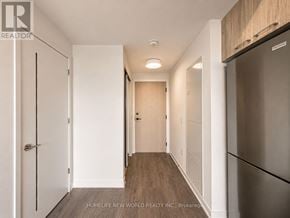 Toronto (Regent Park) condo for rent - A hallway with a white door on the left and a stainless steel refrigerator on the right.