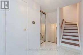 Toronto (L'amoreaux) townhouse for rent - A white door with a gold knob is on the left and a staircase with a red and white striped runner is on the right.