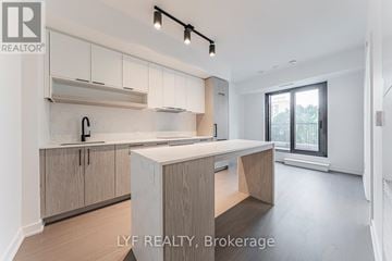 Toronto (Forest Hill South) condo for rent - A modern kitchen with white cabinets and a central island.