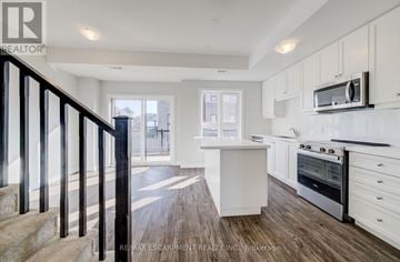 Hamilton (Waterdown) townhouse for rent - A kitchen with white cabinets and a black staircase.