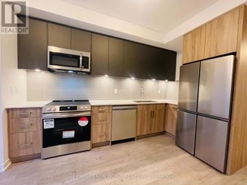 Toronto (Englemount-Lawrence) townhouse for rent - A modern kitchen with wooden cabinets and stainless steel appliances.