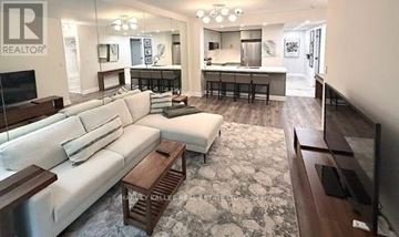 Toronto (St. Andrew-Windfields) condo for rent - A living room with a white couch and a television.