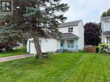 Ottawa apartment for rent - A white house with a blue door and a tree in front.