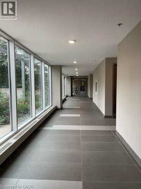 Waterloo condo for rent - A long hallway with a tiled floor and windows on one side.