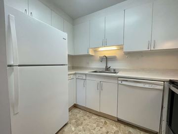 Honolulu apartment for rent - A white refrigerator is in a kitchen with white cabinets.