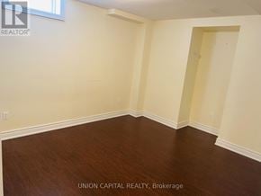 Oshawa (Taunton) apartment for rent - A room with wooden flooring and white walls.