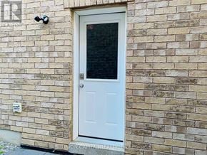 Oshawa (Taunton) apartment for rent - A white door with a window is on a brick wall.