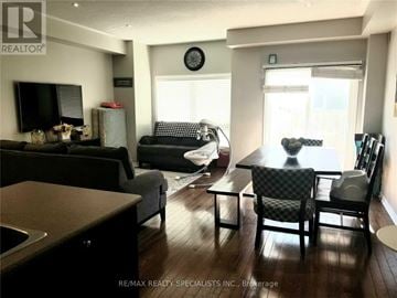 Kitchener townhouse for rent - A living room with a black couch and a wooden floor.