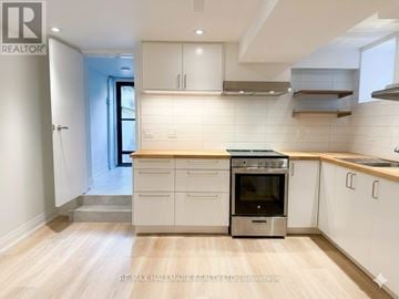 Toronto (Trinity-Bellwoods) apartment for rent - A kitchen with white cabinets and a wooden floor.
