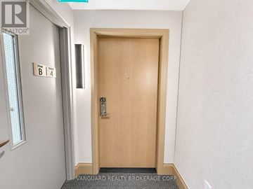 Vaughan (Vaughan Corporate Centre) condo for rent - A wooden door with a handle and a sign above it that says "B 4".