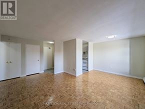 Toronto (Mount Olive-Silverstone-Jamestown) condo for rent - A room with wooden flooring and white walls, with a door on the left and a kitchenette in the background.