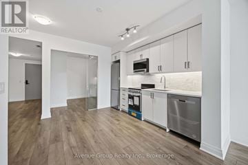 Toronto (Bathurst Manor) condo for rent - A modern kitchen with white cabinets and stainless steel appliances.