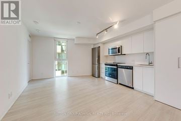 Toronto (Clanton Park) condo for rent - A spacious kitchen with white cabinets and stainless steel appliances.
