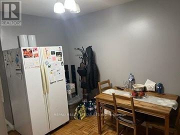Toronto (Rockcliffe-Smythe) apartment for rent - A kitchen with a white fridge, a wooden table with chairs, and a person standing in the background.