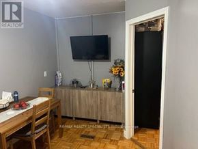 Toronto (Rockcliffe-Smythe) apartment for rent - A dining room with a wooden table and chairs, a flat screen TV mounted on the wall, and a door leading to another room.