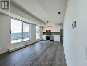 Brantford condo for rent - A spacious kitchen with white cabinets and a large window overlooking the outdoors.