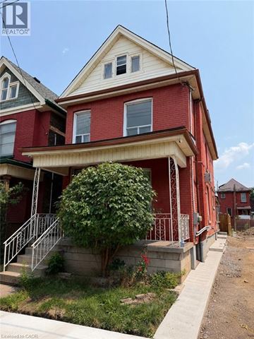 Hamilton apartment for rent - A red house with a white window and a tree in front.