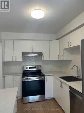 Whitby (Pringle Creek) townhouse for rent - A kitchen with white cabinets and a black stove top oven.