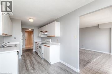 Waterloo condo for rent - A well-lit kitchen with white cabinets and a wooden door.