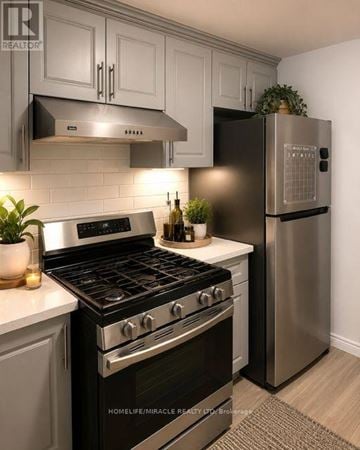 London North (North C) apartment for rent - A modern kitchen with a stainless steel refrigerator and a black stove top oven.