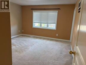 Ajax (South East) townhouse for rent - A room with a carpeted floor, a window with blinds, and a door with a doorknob.