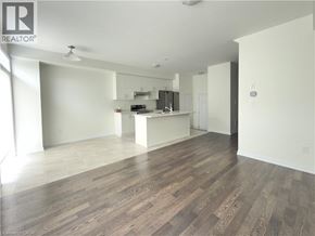 Breslau townhouse for rent - A spacious room with wooden flooring and a kitchen area in the background.