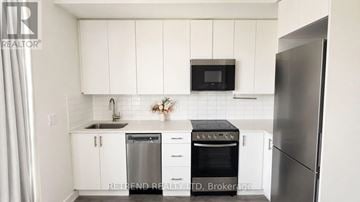 Toronto (Willowdale West) condo for rent - A kitchen with white cabinets and a black fridge.