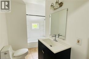 Brantford apartment for rent - A bathroom with a toilet, sink, and mirror.