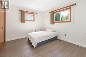 Port Colborne (Sugarloaf) apartment for rent - A bedroom with a bed, wooden floors, and two windows.